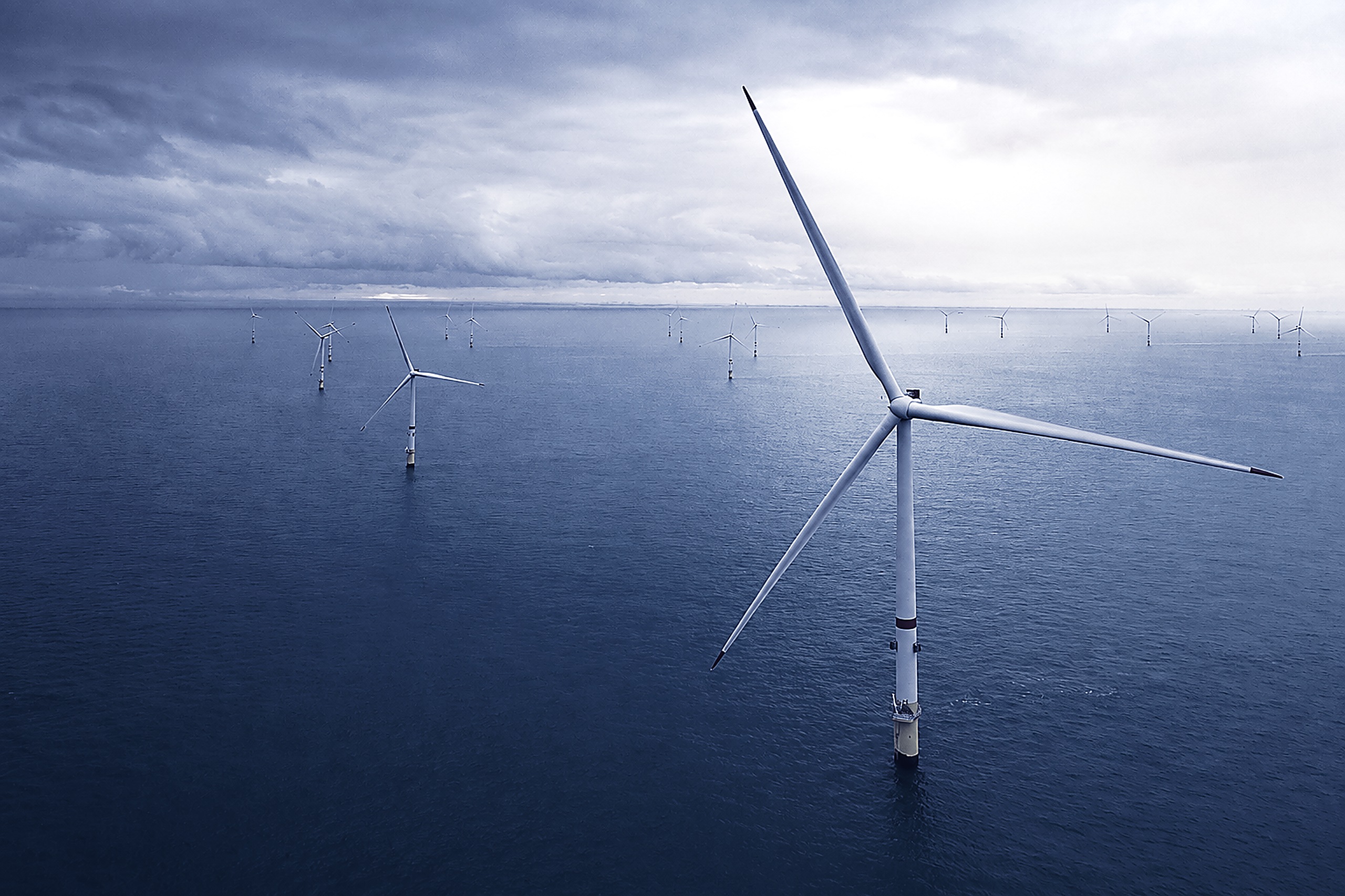 An offshore wind farm at dusk, turbines running to the horizon
